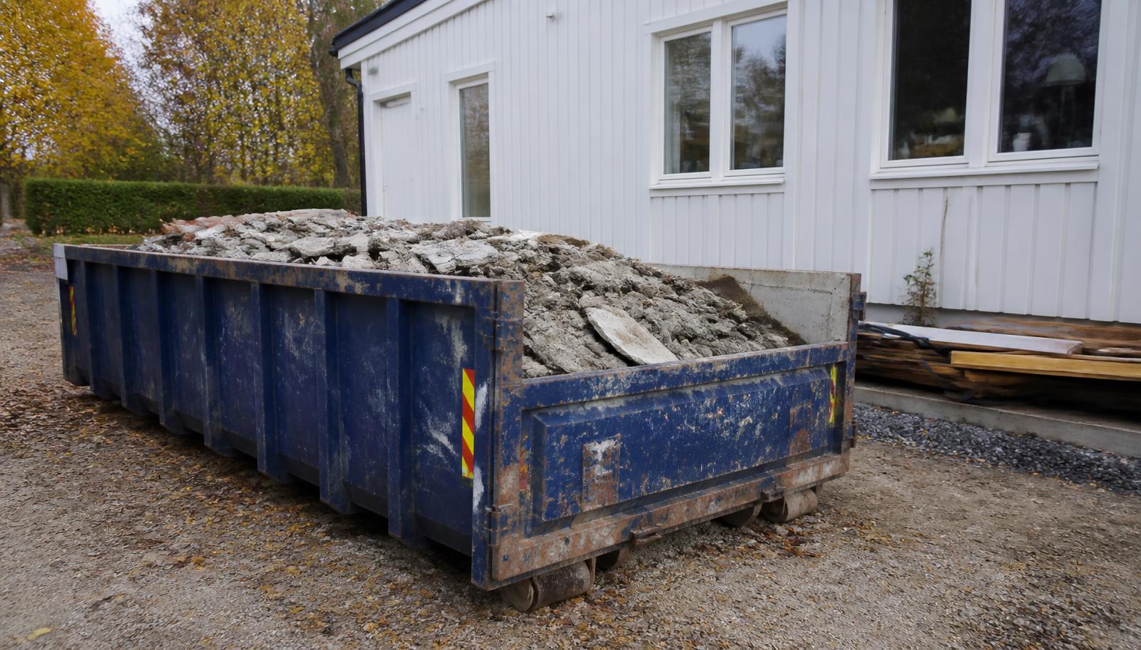 Sinine konteiner eramaja hoovis täis betoonist lammutusjäätmeid