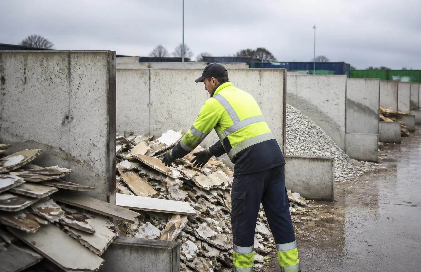 Helkurvestis töötaja sorteerib ehitusjäätmeid betoonist sorteerimisboksidesse